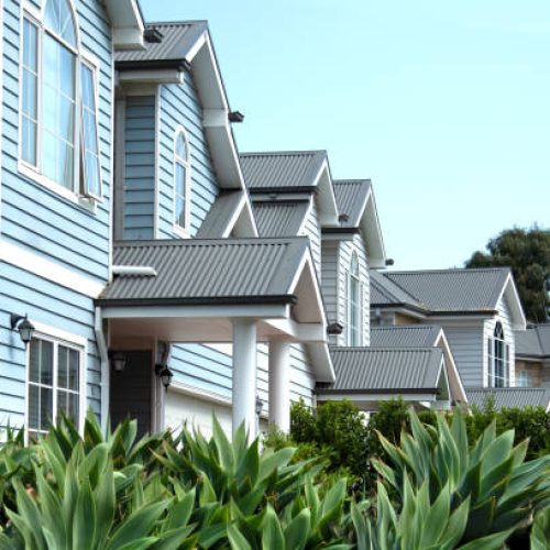 Frontal view of double-story townhouses characterized by their distinctive weatherboard wall cladding and corrugated metal roofs